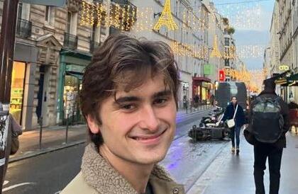 Canon Stringer smiling on a street with string lights above.